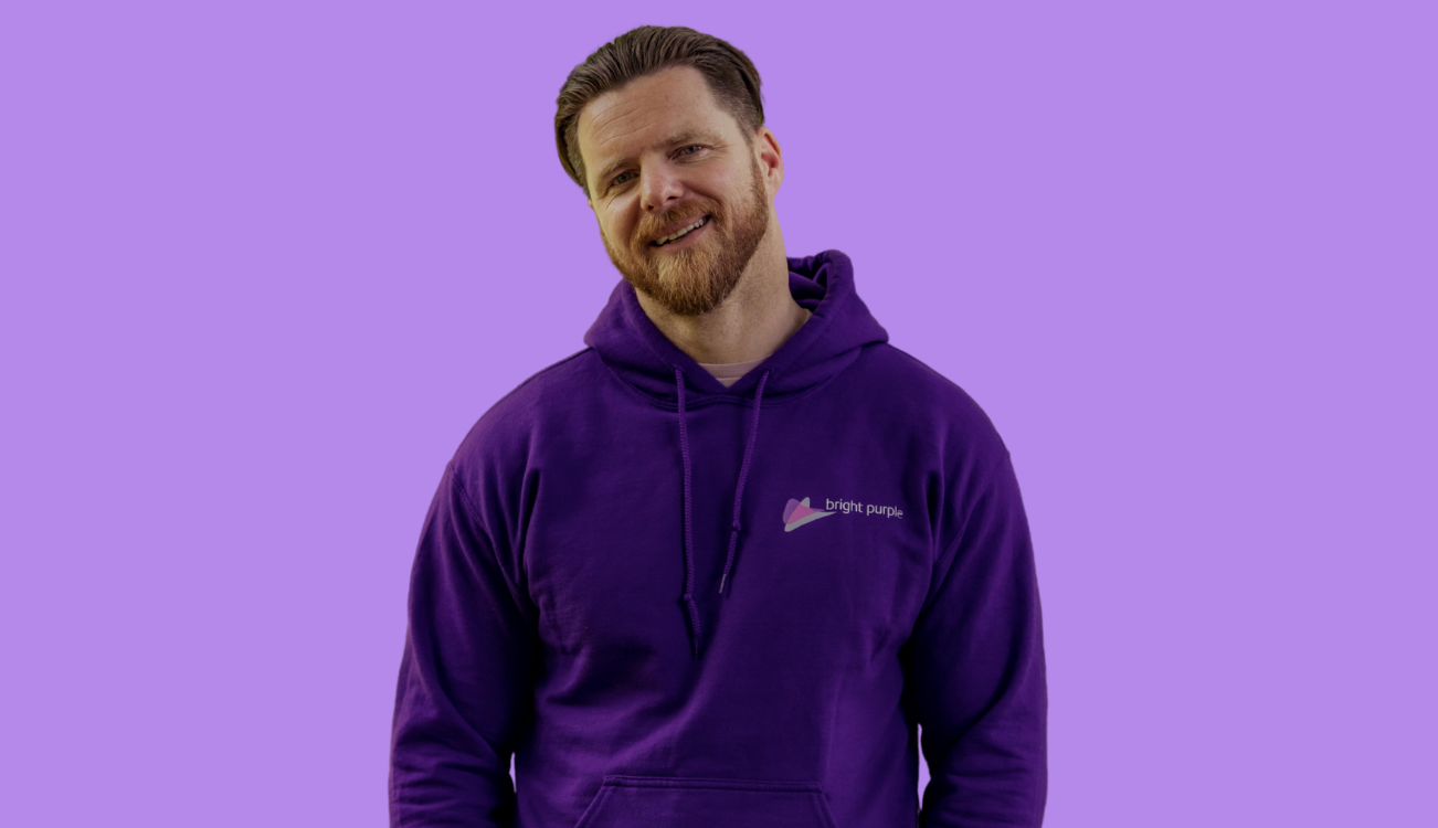 Picture of Chris Murphy wearing a purple hoodie with the Bright Purple logo