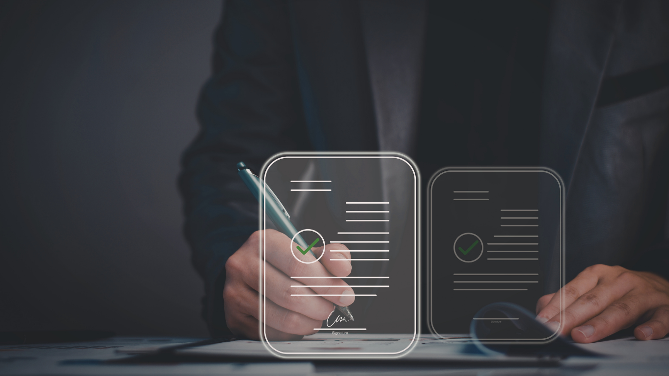 Person signing a physical contract with a pen, two electronic contracts in the foreground 